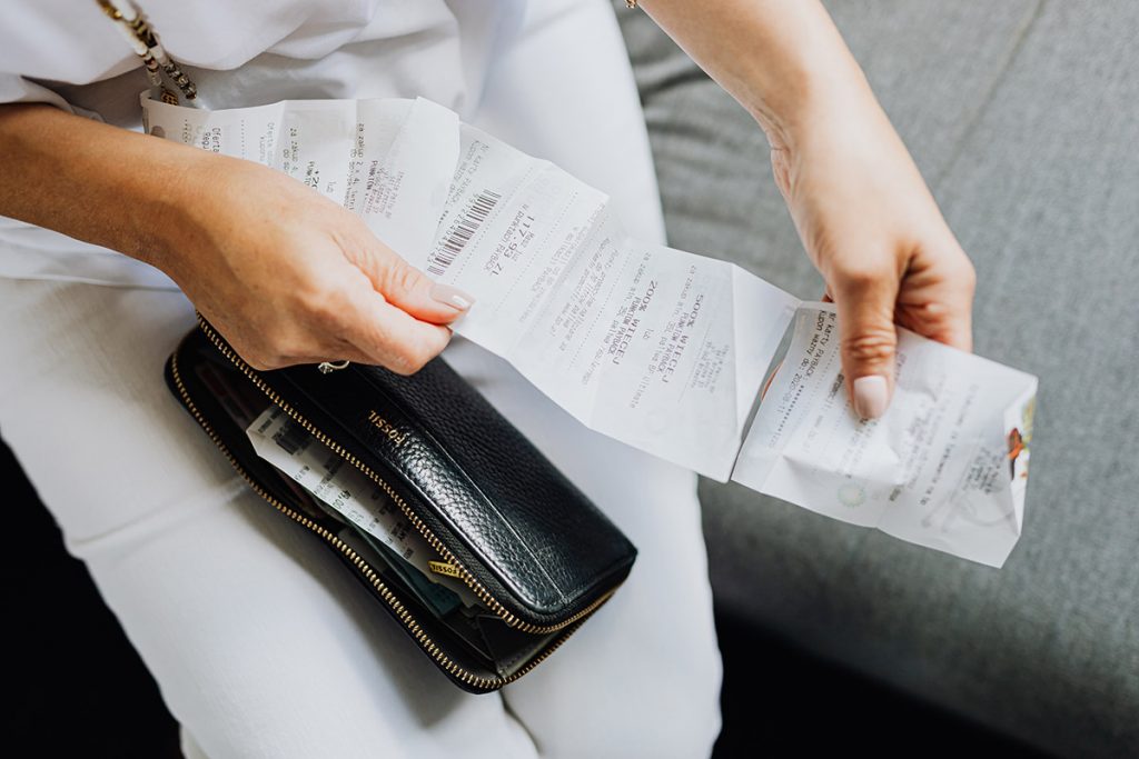 Close up of a woman holding out two receipts.